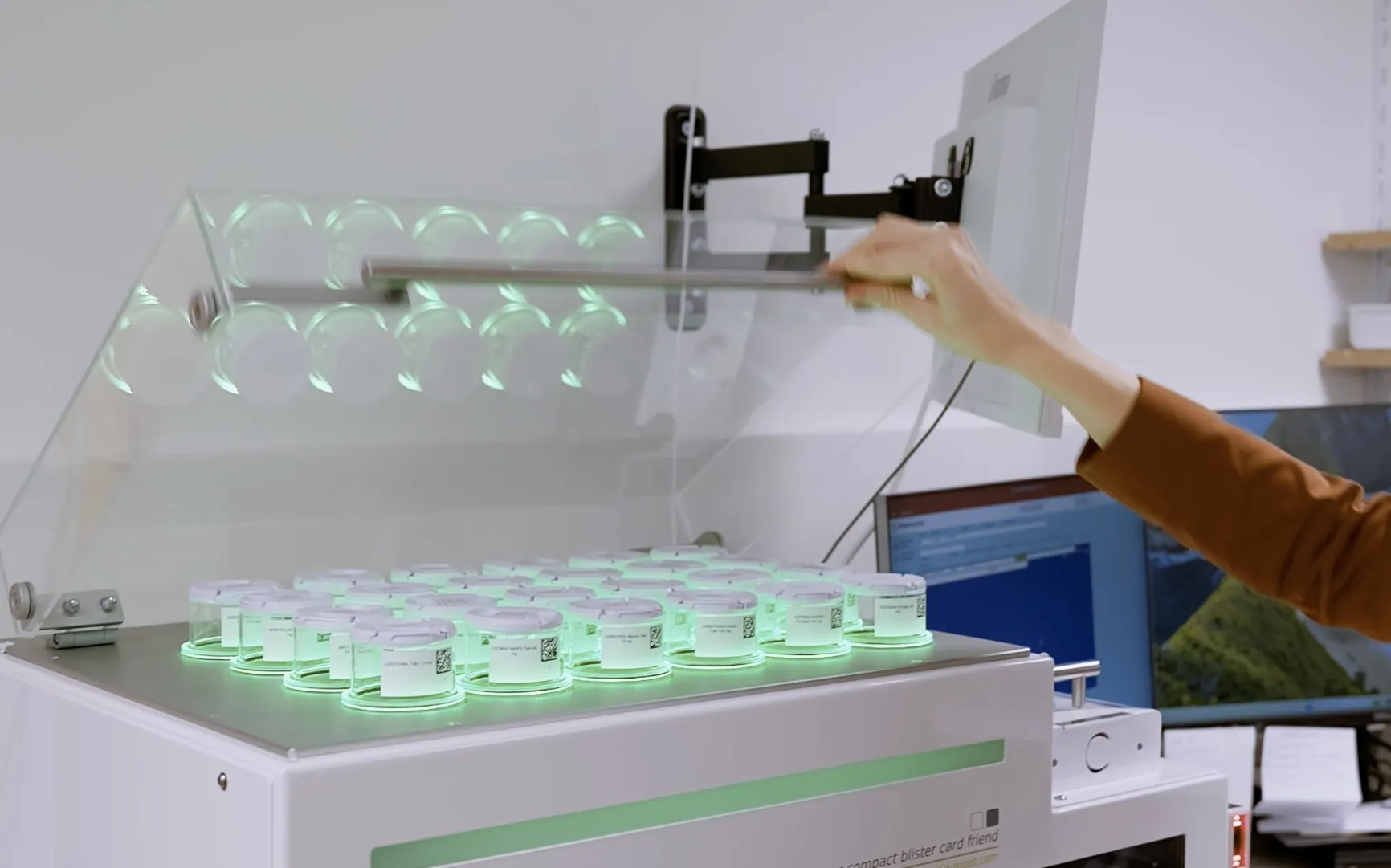 Hand an der geöffneten Blistermaschine mit grün beleuchteten Wochendosen